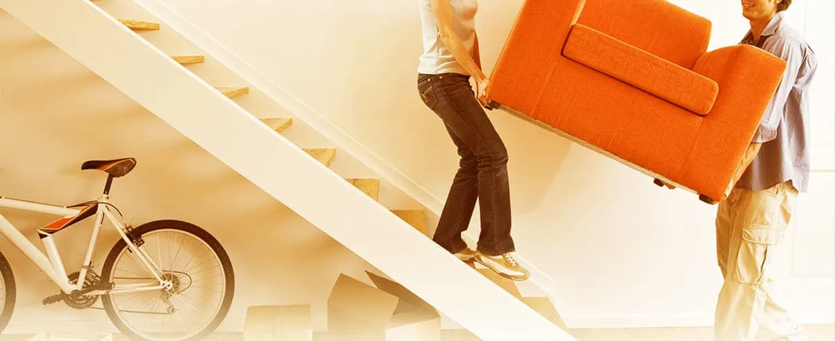 Two movers carefully wrapping furniture for a move.